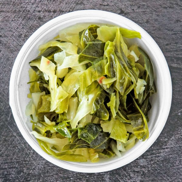 A white bowl filled with a mix of cooked collard greens and cabbage, seen from above.